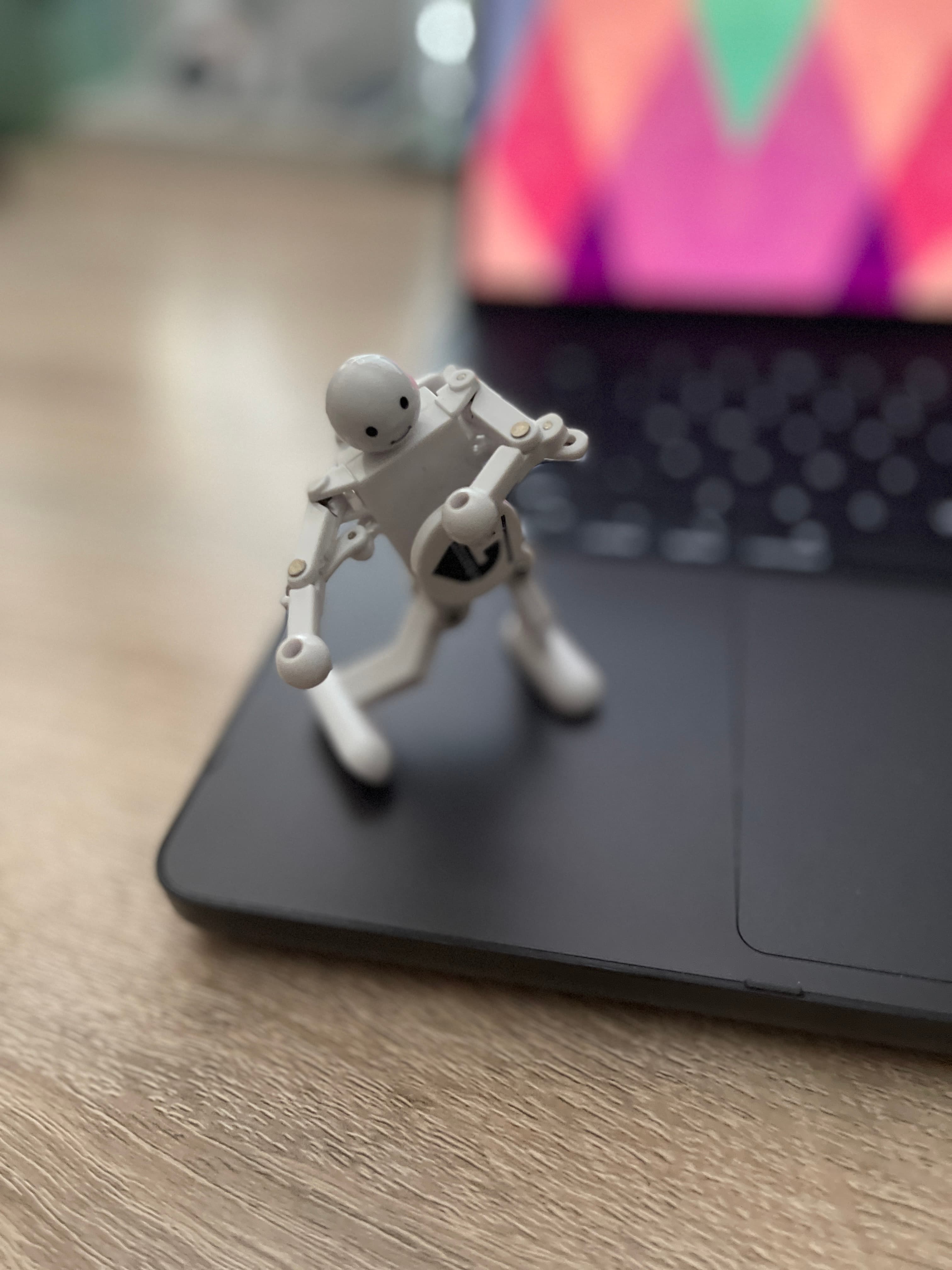 Small white robot figurine standing on an open laptop